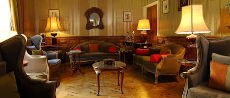 Una habitación tradicional con un conjunto de sofá, sillones, una mesita de centro y lámparas.