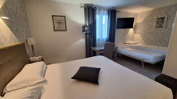 A hotel room with a large bed, a desk, a chair, a TV, and a window with curtains.