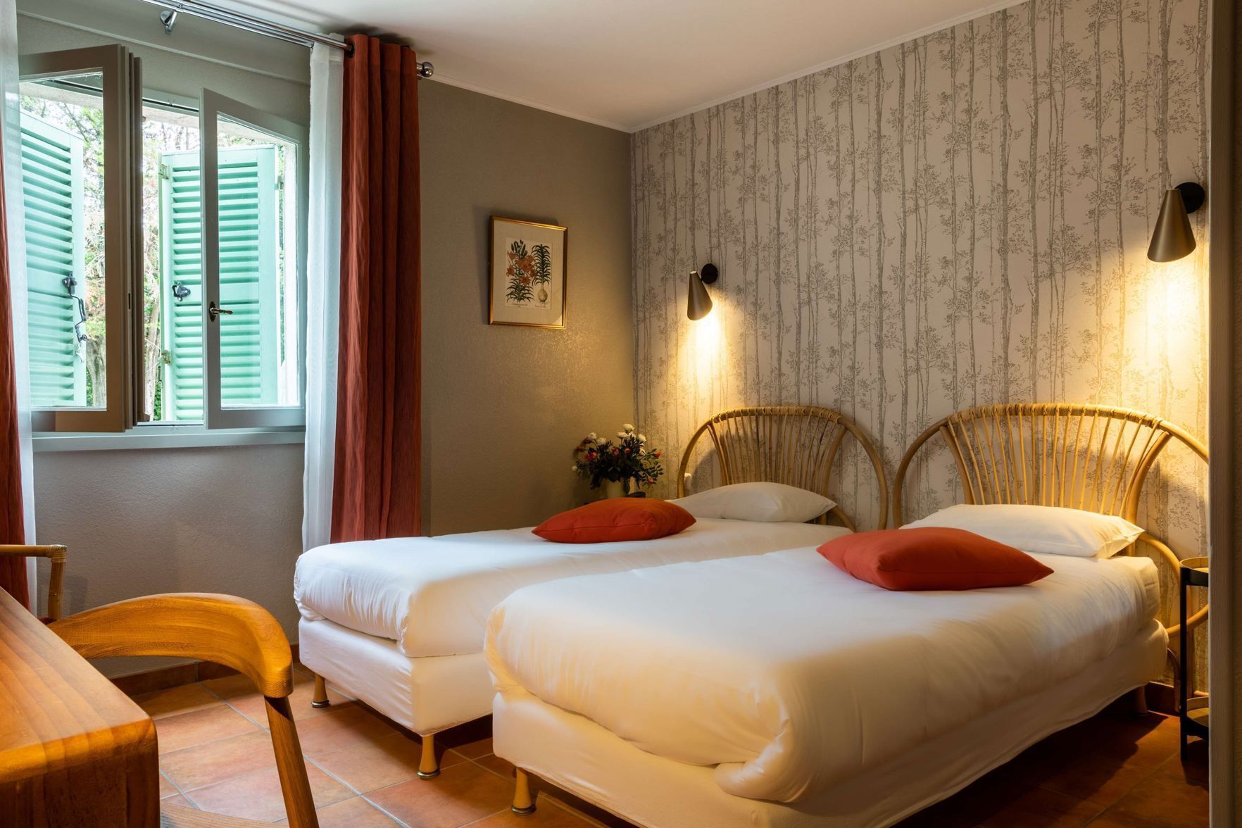 A bedroom with two beds, a wooden chair, a desk, and a window with curtains.
