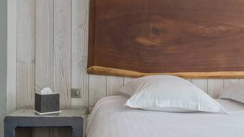 A neatly made bed with white linens, a wooden headboard, and a bedside table with a tissue box.