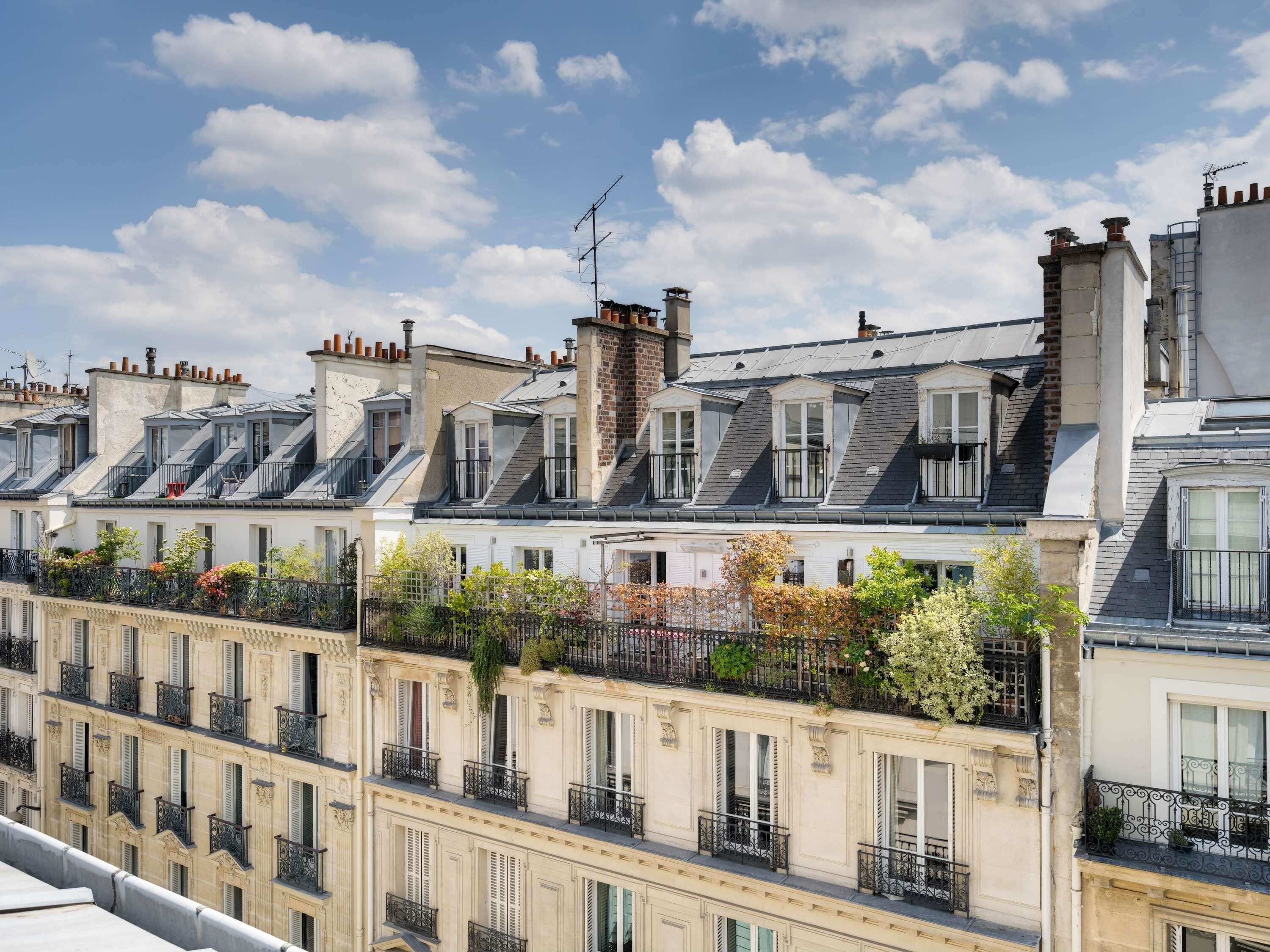 Una hilera de casas urbanas europeas clásicas con techos pronunciados, ventanas de tejado y balcones ornamentados.
