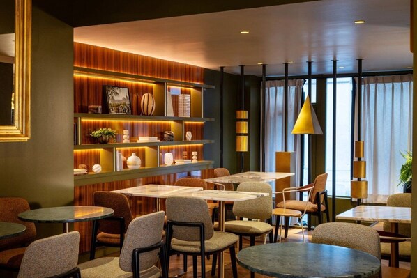 A modern interior with multiple seating areas, a wooden accent wall, and a large window with curtains.