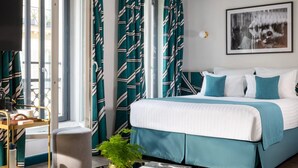 A modern bedroom with a bed, a bedside table with a lamp, a window with curtains, and a wall-mounted TV. - Hôtel Aoriste & Spa (Paris)