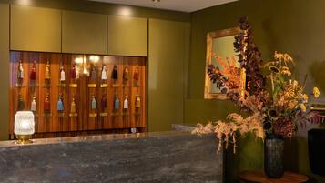 A reception area with a wooden panel wall, a marble counter, and a mirror with a floral arrangement.
