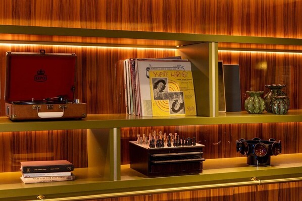A shelf with a vintage suitcase, a selection of books, a chess set, and decorative vases. - Hôtel Aoriste & Spa (Paris)