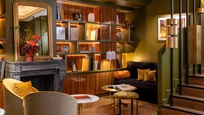 A cozy living room with a fireplace, a bookshelf, a sofa, and a staircase. - Hôtel Aoriste & Spa (Paris)