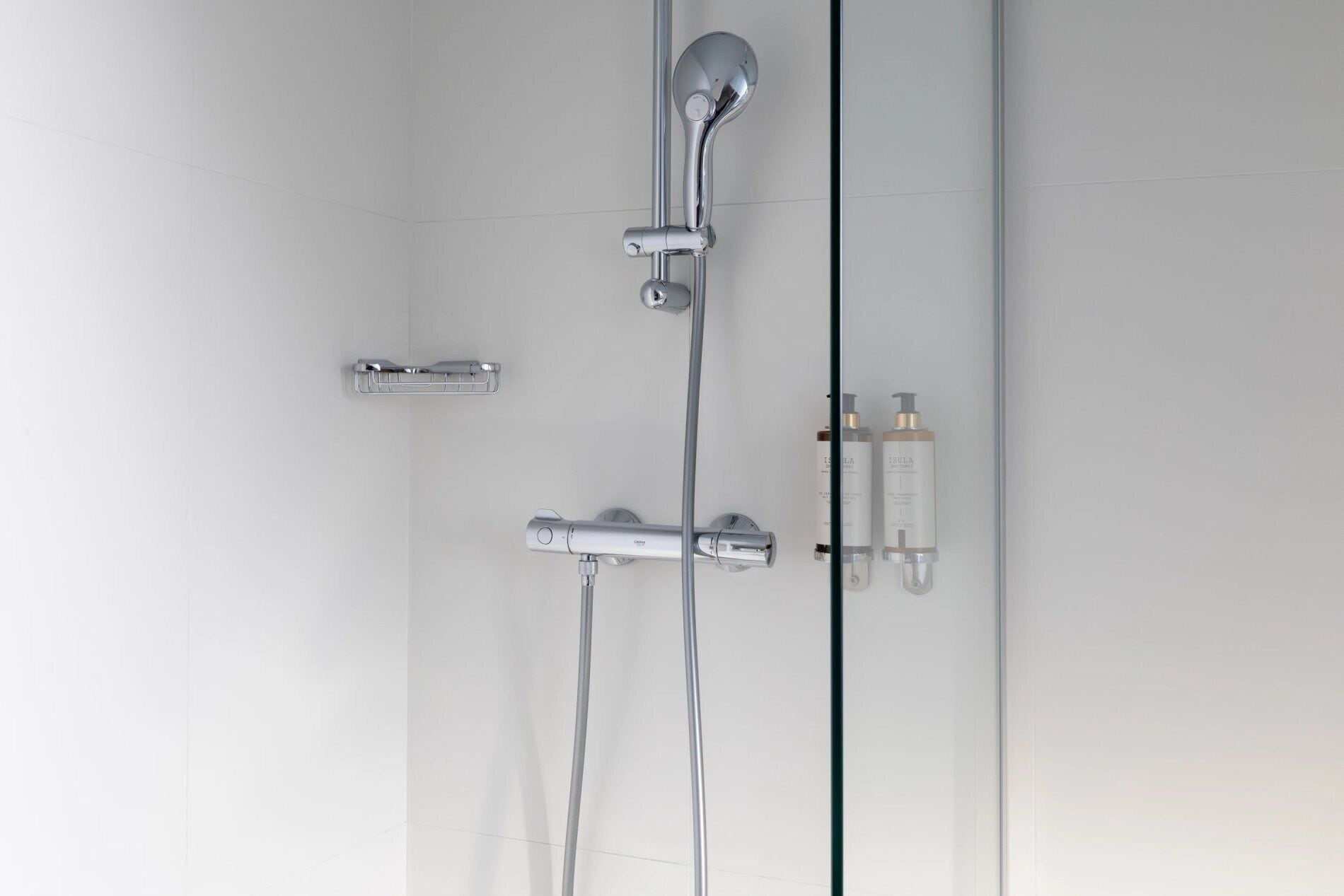 A modern shower with a handheld showerhead and a wall-mounted faucet.
