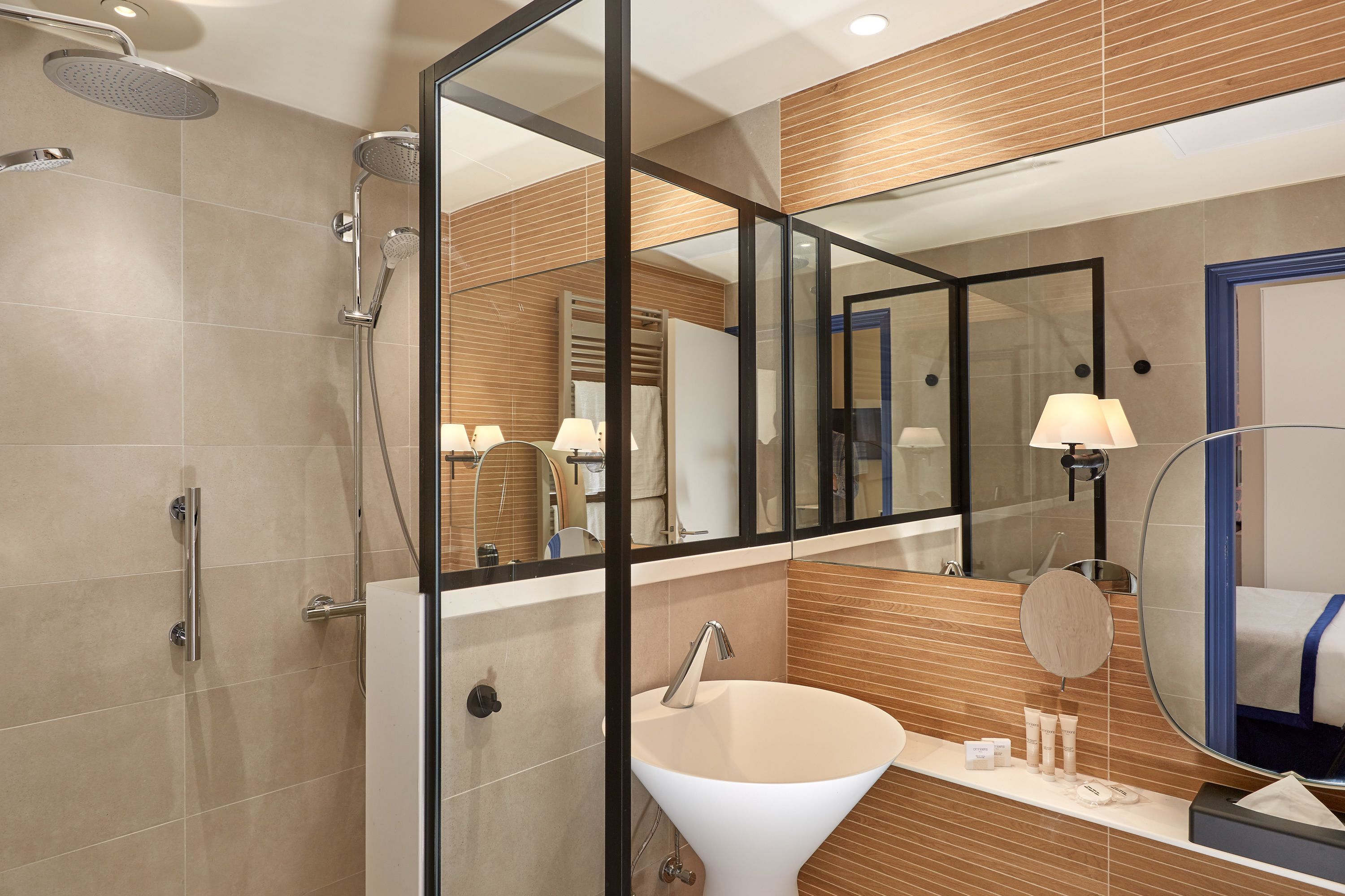Une salle de bain moderne avec une douche à parois de verre, un lavabo blanc et un grand miroir.