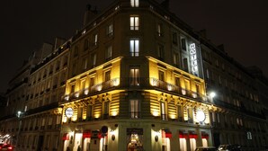 A historic hotel with a classic facade, multiple balconies, and illuminated signage. - Hotel de Sevigne (Paris)