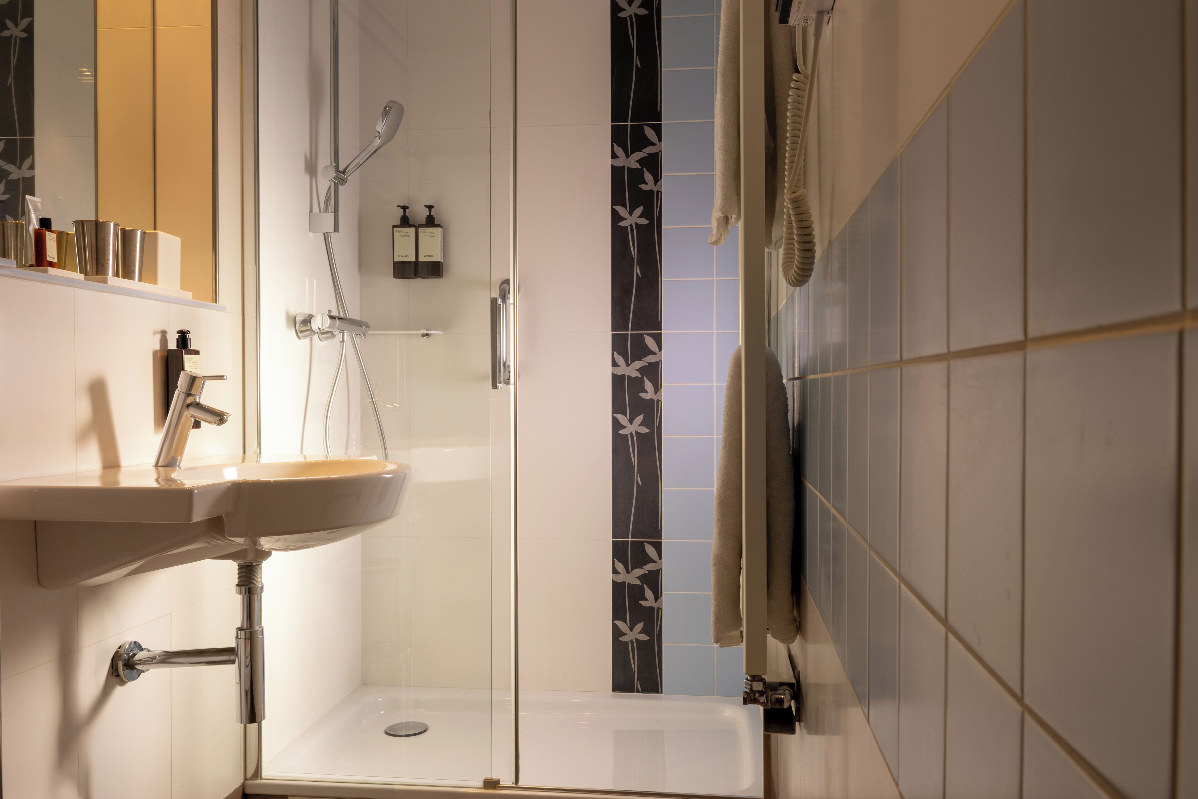 Et badeværelse med vask, brusekabine i glas og toilet.