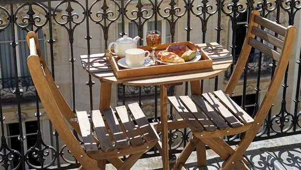 A balcony with a table set for two, featuring a teapot, cups, and pastries. - Hotel de Sevigne (Paris)