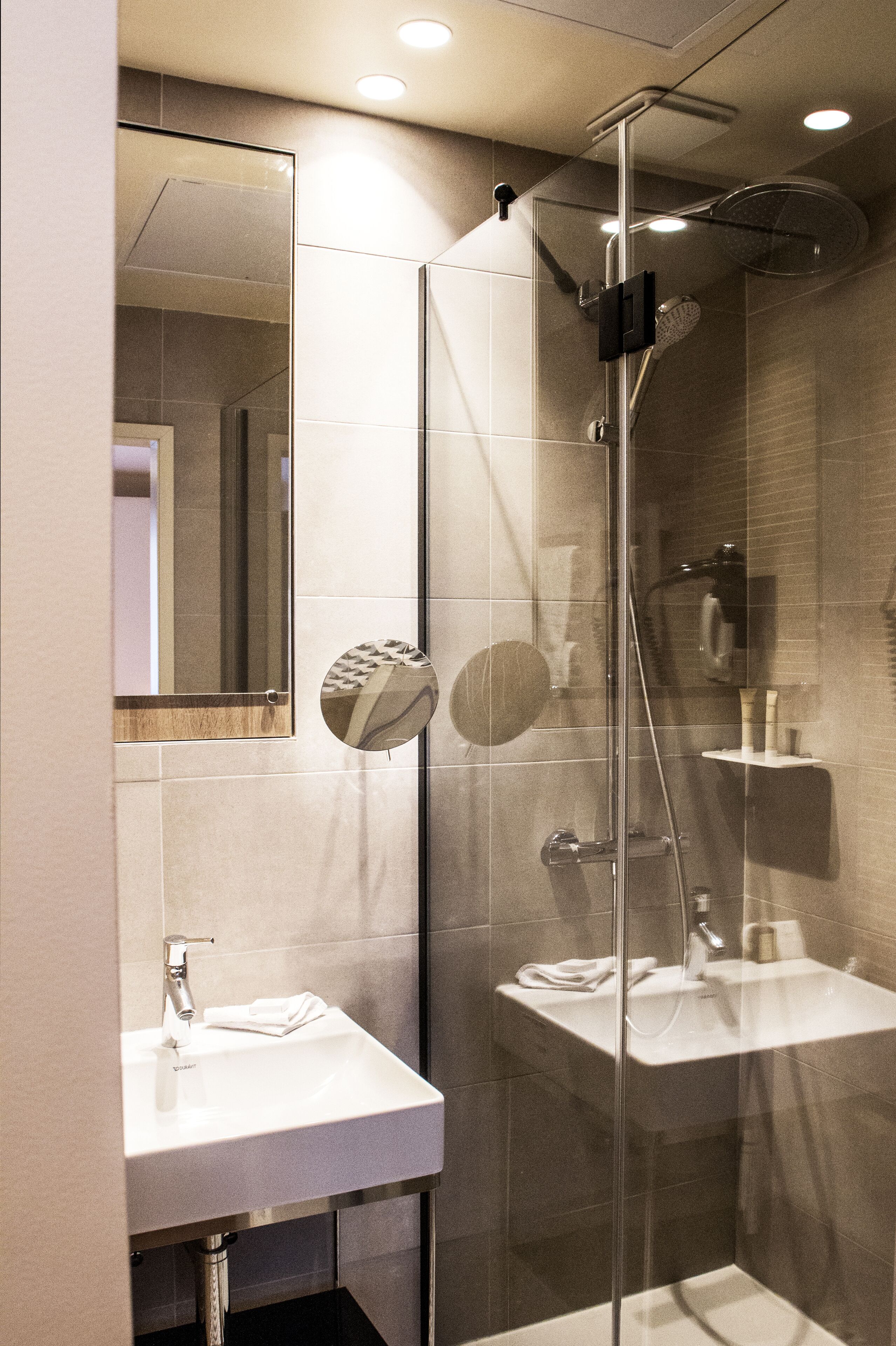 A modern bathroom with a glass-enclosed shower, a sink, and a mirror.