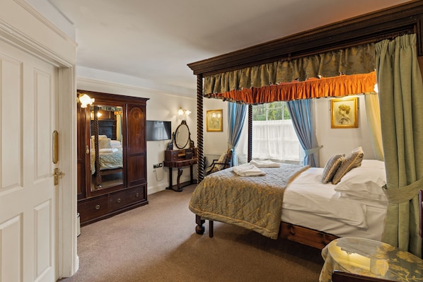 Une chambre à coucher avec un lit à baldaquin, une armoire en bois, un miroir et une table de chevet.