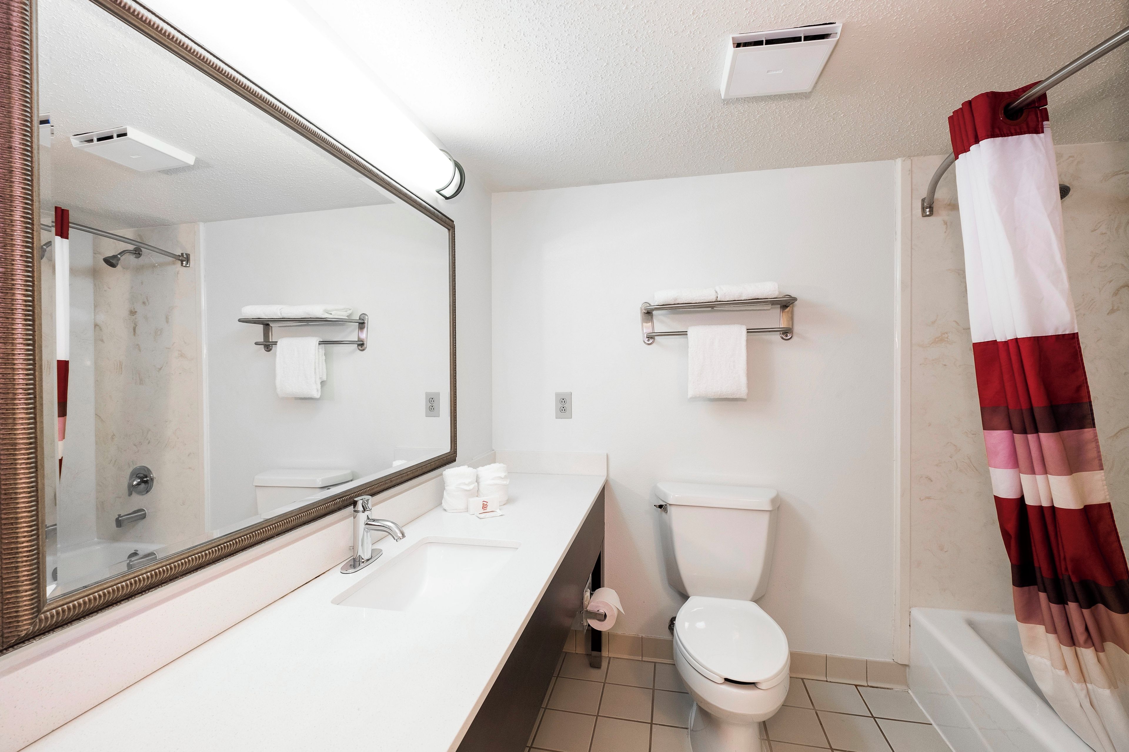 Un baño con lavamanos blanco, un espejo, inodoro y cortina de ducha.