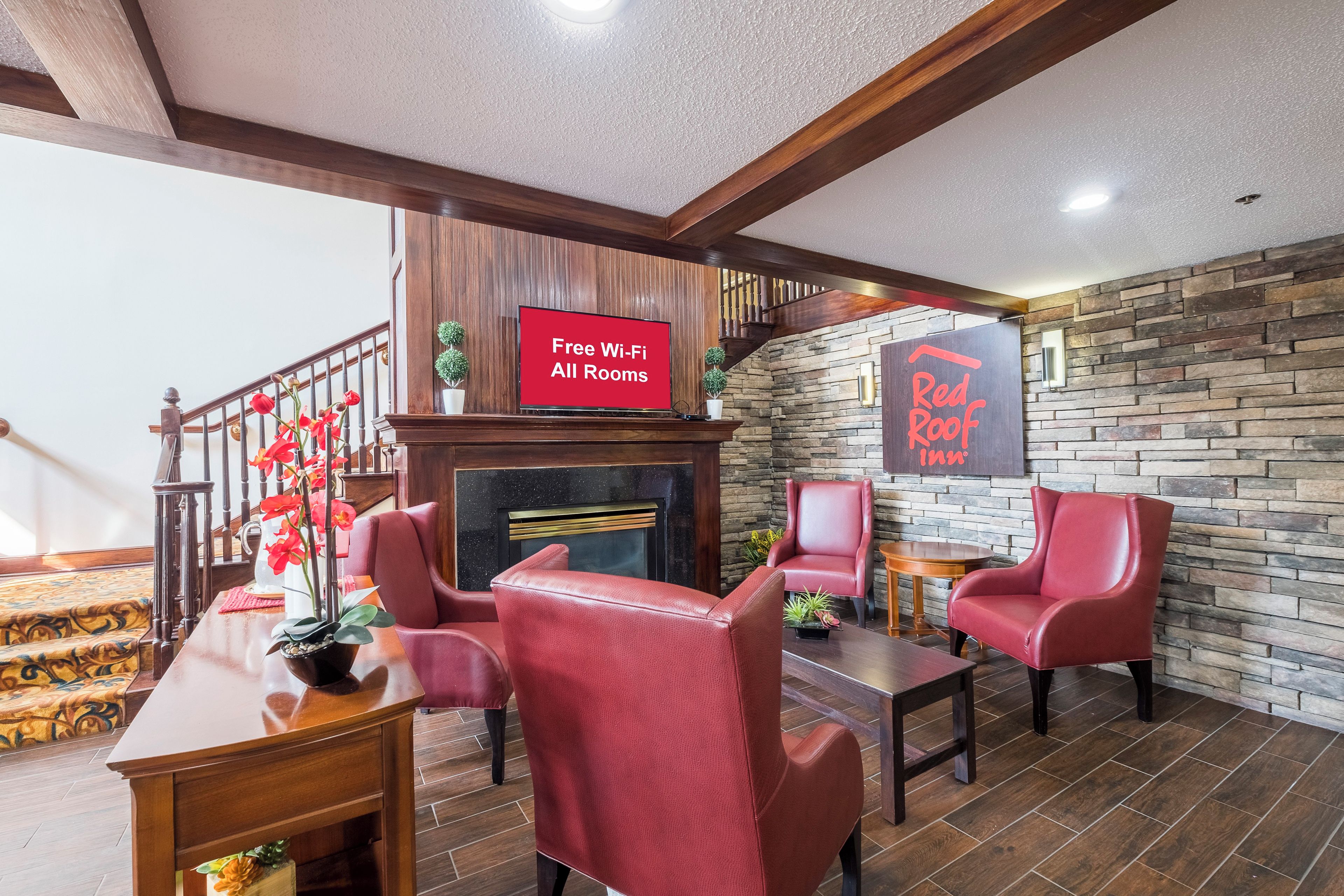 Vestíbulo de hotel con escalera, chimenea y un cartel que indica Wi-Fi gratuito en todas las habitaciones.