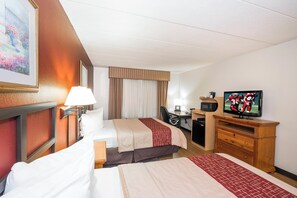 A hotel room with two beds, a desk, a television, and a painting on the wall.