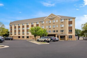 A multi-story hotel with a flat roof, a parking lot, and several cars parked in front. - Country Inn & Suites by Radisson, Sioux Falls (Sioux Falls)