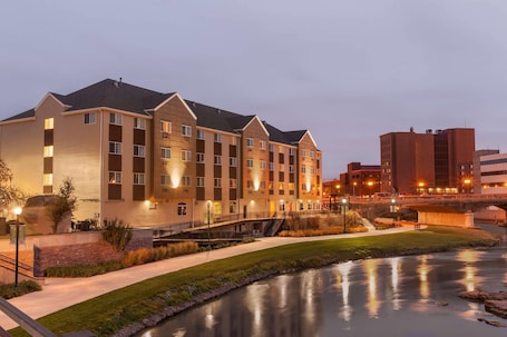 A multi-story hotel with a flat roof, a landscaped area with a water feature, and a bridge connecting to another building.. Country Inn & Suites by Radisson, Sioux Falls