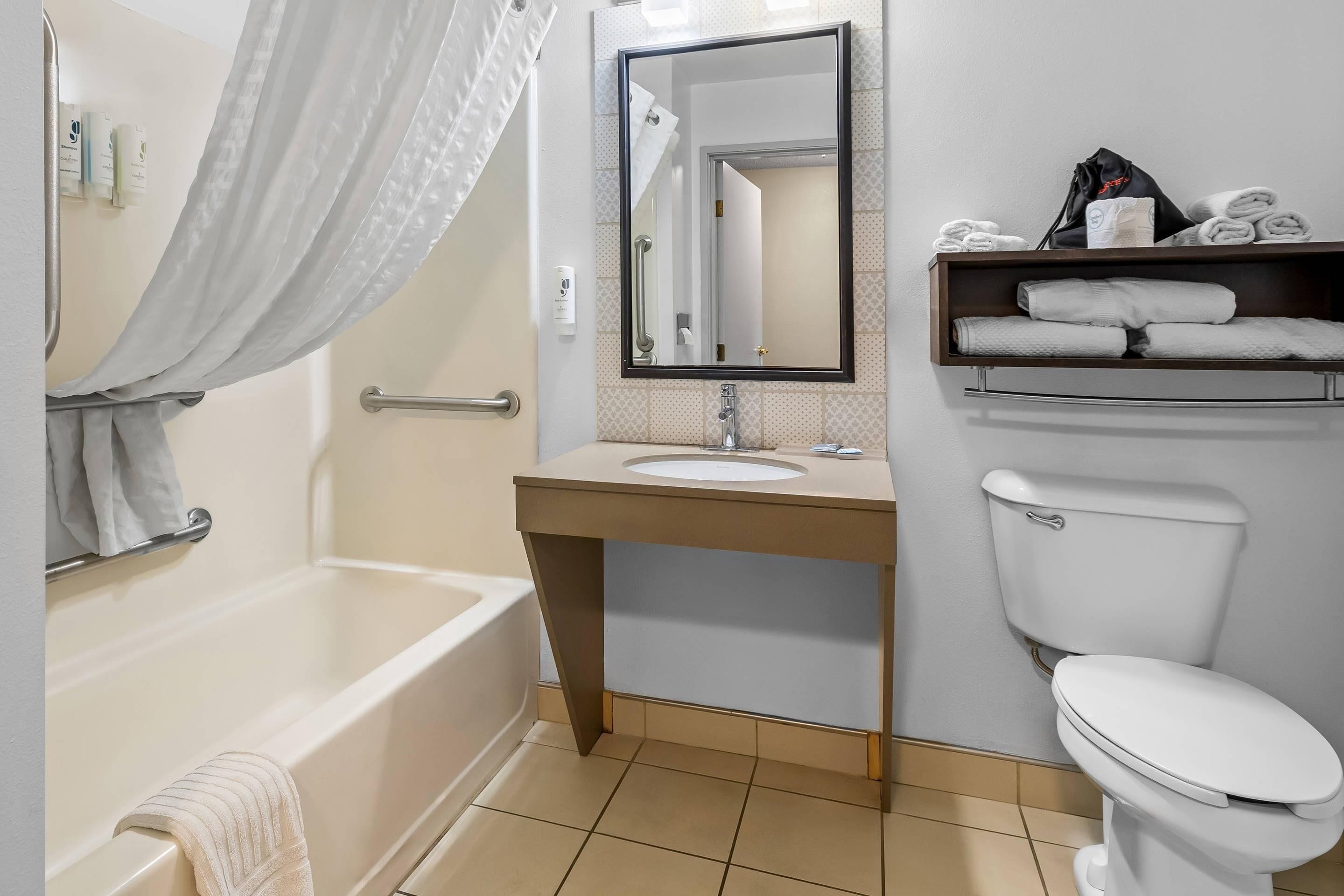 A bathroom with a bathtub, a sink, a toilet, and a towel rack.