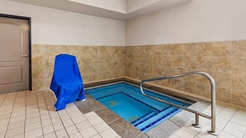 A swimming pool with a metal handrail, tiled walls, and a door.