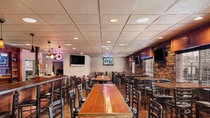 A restaurant with a long wooden table, multiple chairs, a bar area, and a stone wall. - Country Inn & Suites by Radisson, Sioux Falls (Sioux Falls)