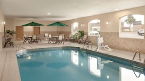 A swimming pool with lounge chairs and umbrellas, a view of the outside, and a sign indicating the hotel name. - Country Inn & Suites by Radisson, Sioux Falls (Sioux Falls)