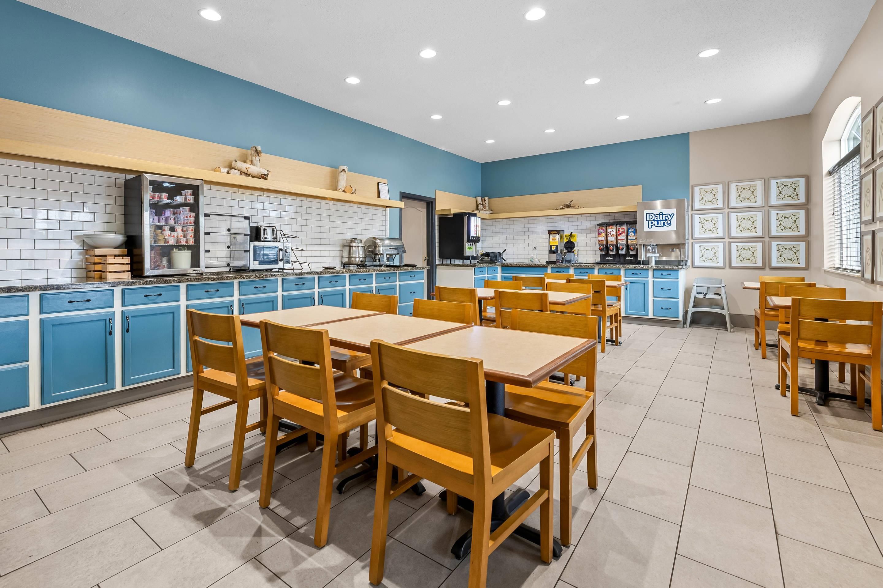 A restaurant with blue cabinets, wooden tables, and chairs.