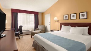 A hotel room with a large bed, a desk with a computer, a chair, a lamp, and three framed pictures on the wall. - Country Inn & Suites by Radisson, Sioux Falls (Sioux Falls)