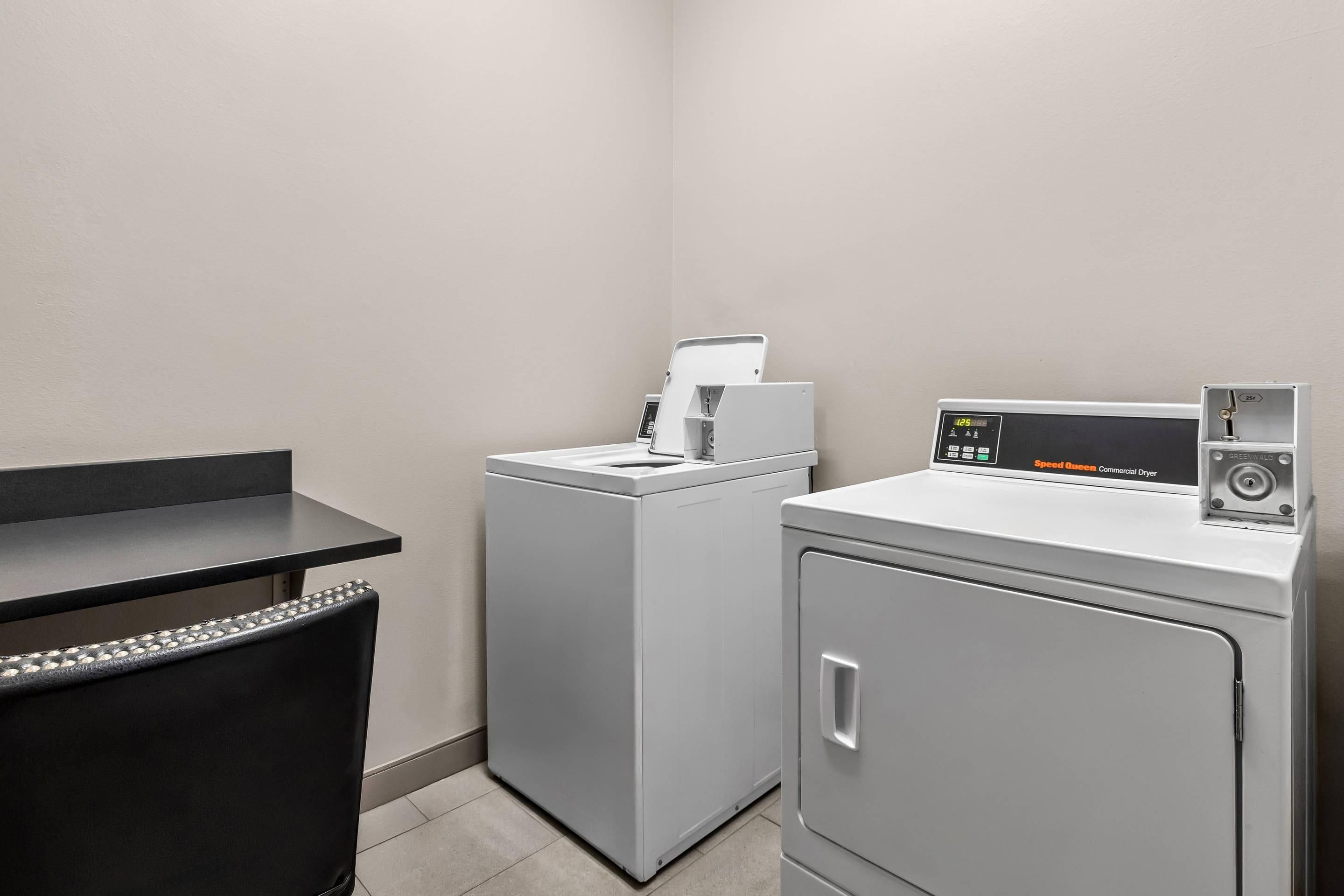 A laundry area with a washing machine, dryer, and a desk with a chair.