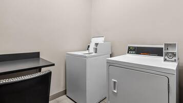 A laundry area with a washing machine, dryer, and a desk with a chair.