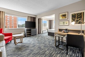 A hotel room with a TV, a desk, a chair, a bed, and a window with a view of buildings. - Country Inn & Suites by Radisson, Sioux Falls (Sioux Falls)