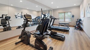 A gym with cardio machines, mirrors, and a window with blinds. - Best Western Eau Claire South (Eau Claire)