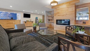 A modern living room with a glass coffee table, sofas, and a TV mounted on the wall. - Best Western Eau Claire South (Eau Claire)