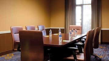A conference room with a long table, six chairs, and water bottles on the table.