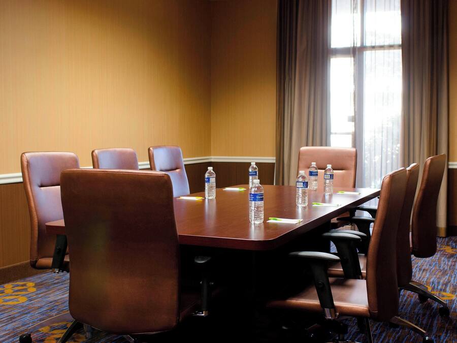 A conference room with a long table, six chairs, and water bottles on the table.