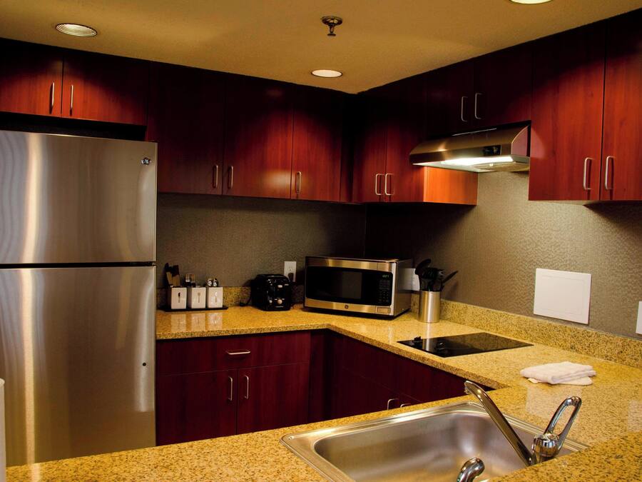 A modern kitchen with stainless steel appliances, granite countertops, and dark wood cabinets.