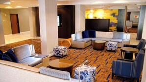 Un vestíbulo de hotel con una zona de estar que incluye sofás, sillones y otomanas.