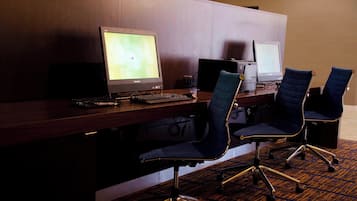 A hotel reception desk with two computer monitors, a keyboard, and two office chairs.