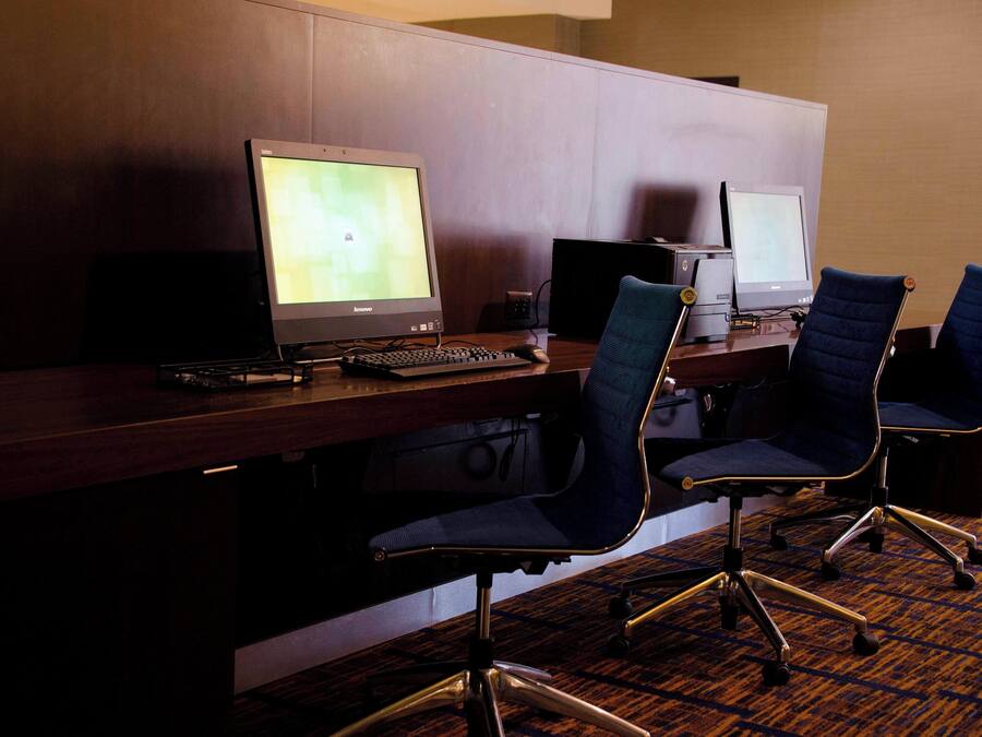 A hotel reception desk with two computer monitors, a keyboard, and two office chairs.