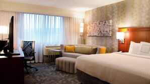 Habitación de hotel con una cama grande, un escritorio con una computadora, una silla y una mesita.