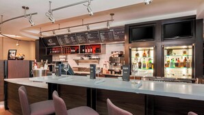 Un bar moderno con una barra larga, diversas opciones de asientos y un menú visible.