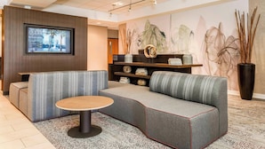 Un moderno vestíbulo con un sofá modular, una mesa redonda, un televisor montado y decoración en la pared.