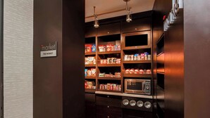 Una kitchenette equipada con microondas, horno y estantes repletos de alimentos.