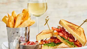 A sandwich with a side of fries and a glass of white wine.