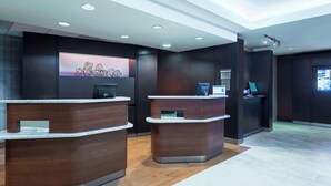 A reception area with two wooden reception desks, a digital screen, and a wall-mounted artwork.