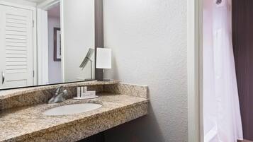 A bathroom with a granite countertop sink, a mirror, a towel rack, and a shower curtain.