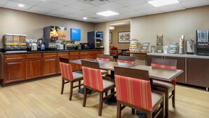 A hotel dining area with wooden tables and chairs, a coffee station, and a microwave. - Comfort Inn & Suites Hamilton Place (Chattanooga)