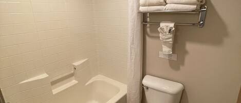 A bathroom with a bathtub, toilet, and towel rack.