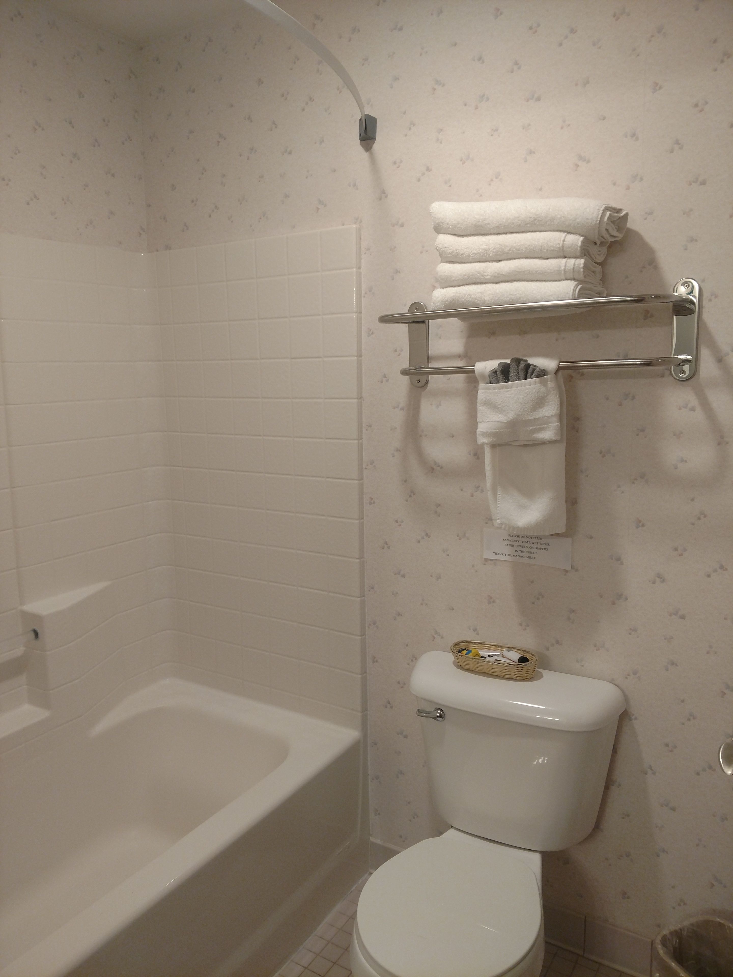 Ein Badezimmer mit einer weißen Badewanne, einer Toilette und einem Handtuchhalter mit gefalteten Handtüchern.