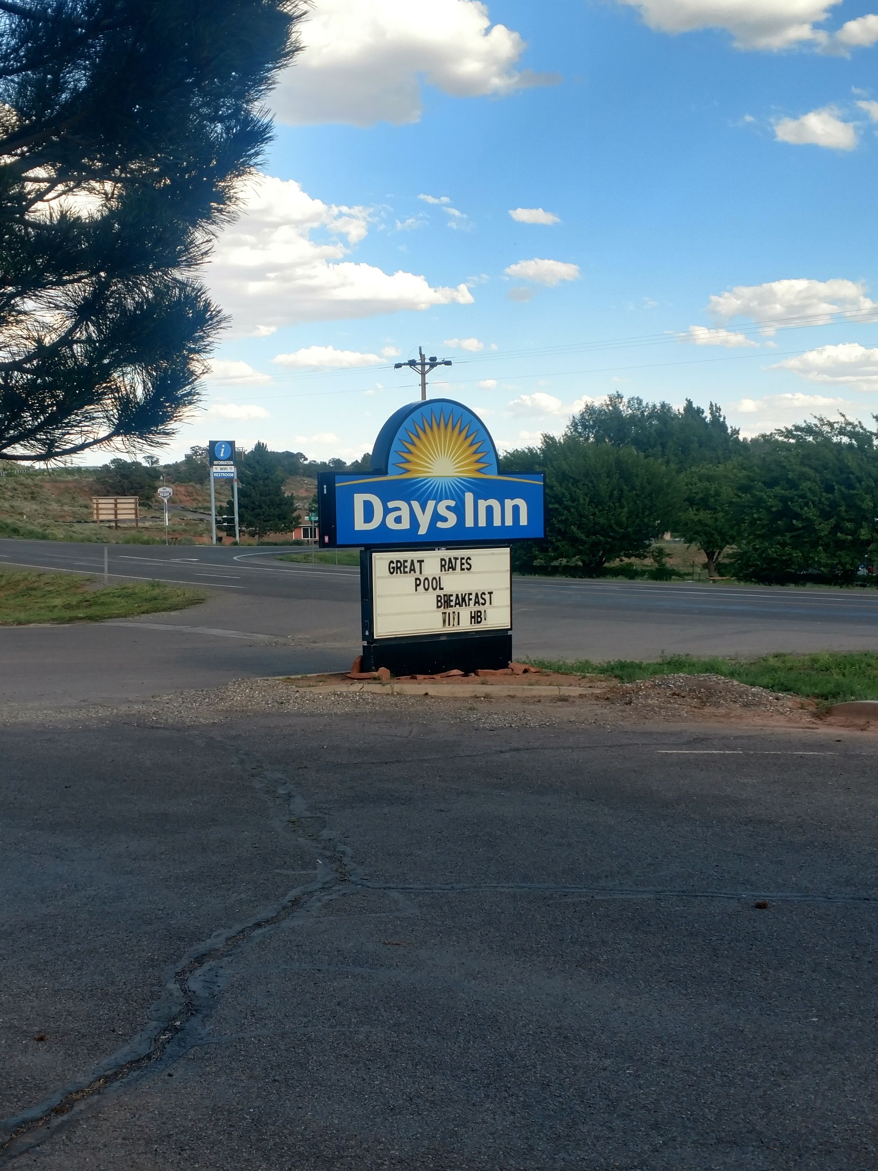 A Days Inn sign with a blue and yellow logo, a signboard advertising great rates, pool, breakfast, and Wi-Fi.